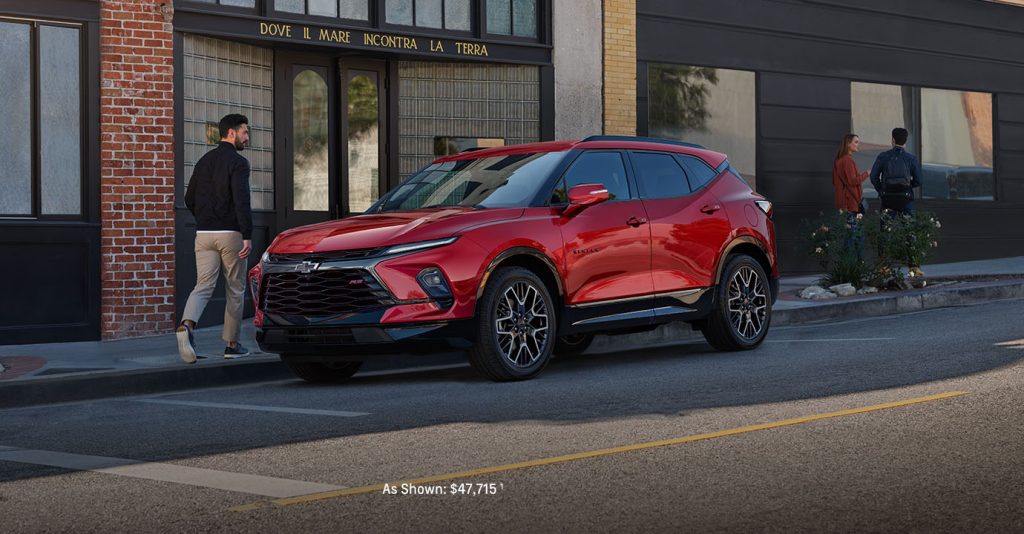 2025 Chevrolet Blazer in vibrant red parked on a city street, showcasing its bold exterior design, sporty front grille.