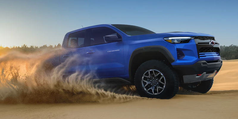 a blue 2026 Chevy Colorado truck drives through golden sand