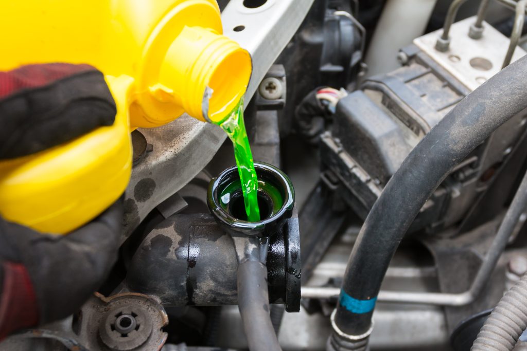 Car coolant being poured into a vehicle engine coolant reservoir