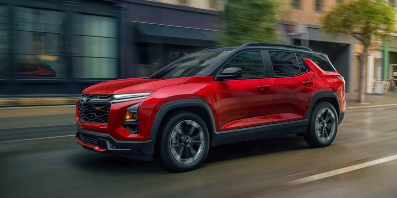 A red 2025 Chevy Equinox driving through the city streets fast.
