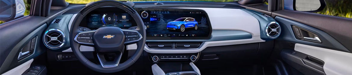 A silver 2025 Chevy Equinox EV parked outside a shopping plaza near Amsterdam, NY.