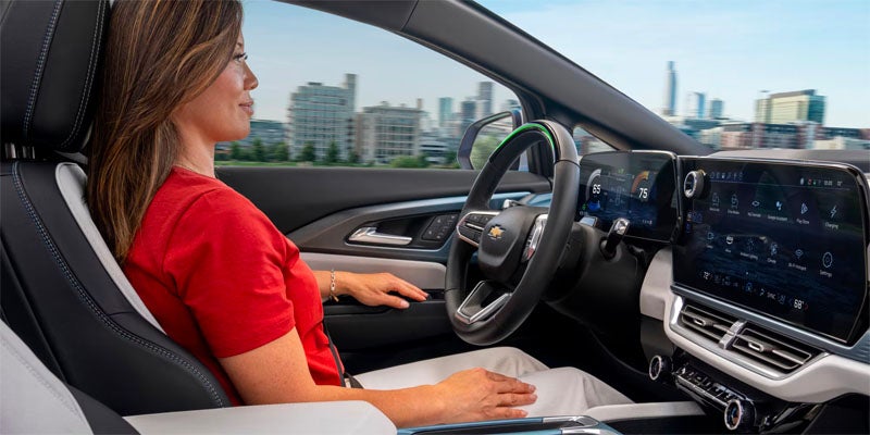 A woman driving a white 2025 Chevrolet Equinox EV, focused behind the wheel.