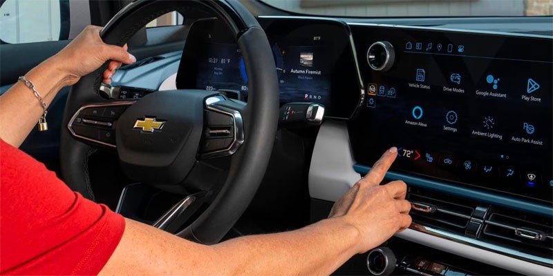 A woman interacts with the touchscreen display while driving the 2025 Chevrolet Equinox EV.