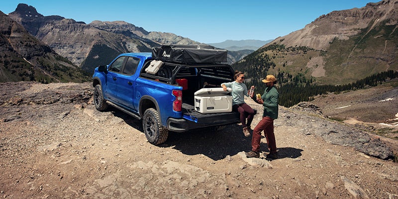 A blue chevy Silverado 1500 parked near a campsite