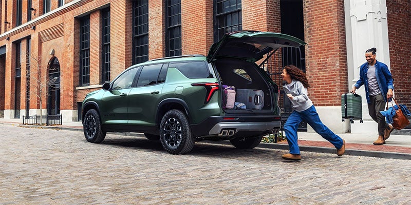 Chevrolet Traverse SUV with open rear cargo area and passengers loading luggage